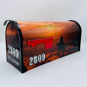 May include: A red mailbox with a sunset scene and a cowboy riding a horse. The mailbox has the number 2809 and the name W.W. Plotzky on it.