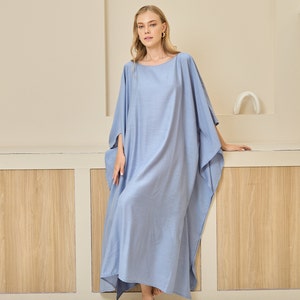 May include: A floor-length, light blue kaftan dress featuring a wide, loose-fitting silhouette with batwing sleeves and a simple round neckline. The garment is made of a solid-colored, lightweight fabric that drapes down to the ankles.