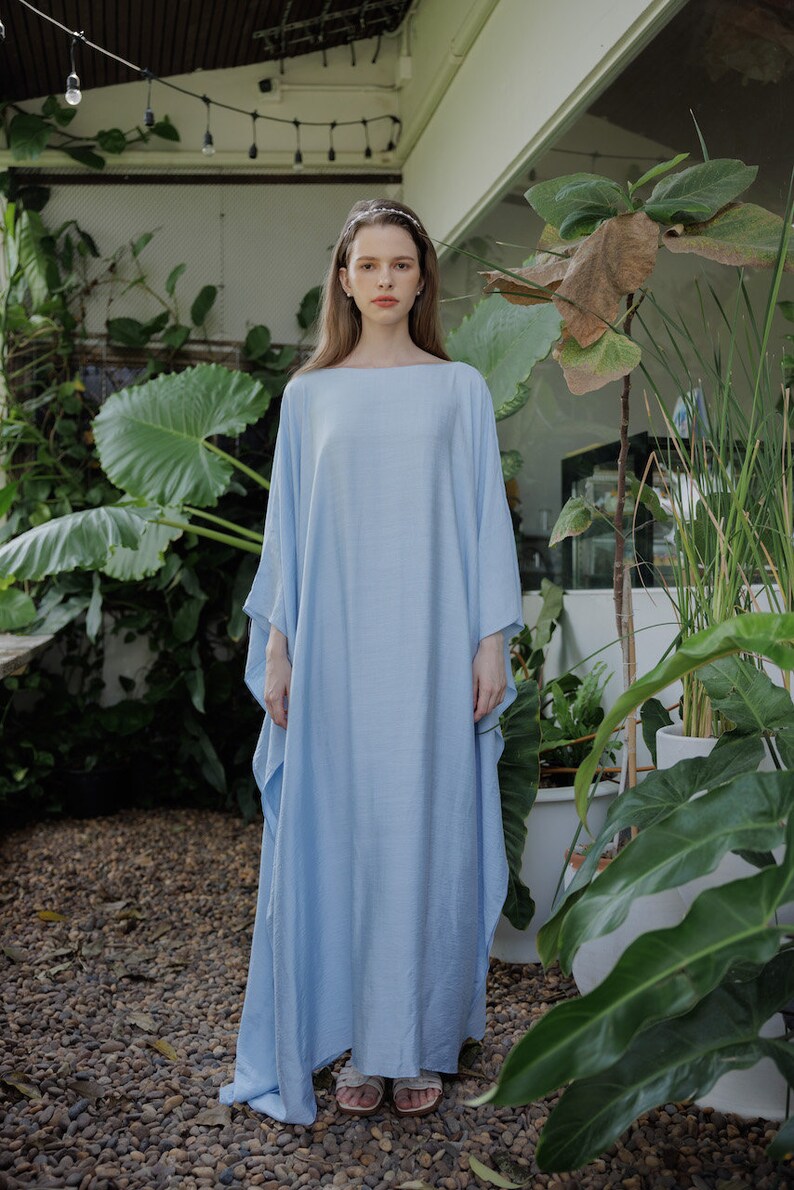 K&ouml;nnte beinhalten: Ein hellblaues Maxikleid mit einer lockeren, flie&szlig;enden Silhouette. Das Kleid hat ein schlichtes, elegantes Design und ist perfekt f&uuml;r ein l&auml;ssiges Sommeroutfit.
