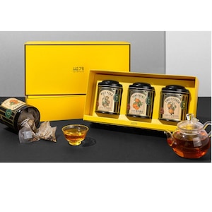 May include: A yellow gift box with three round black tea tins. The tins have labels with illustrations of fruit and the text "Wild Pear", "Tangerine", and "Sweet Citron". The box also has the text "새롭게" on the front.