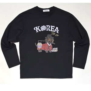 Puede incluir: Camiseta negra de manga larga con un estampado gráfico de un dachshund con un sombrero tradicional coreano y sosteniendo una linterna. El texto "KOREA" y "Yip yip" está impreso en la camiseta.