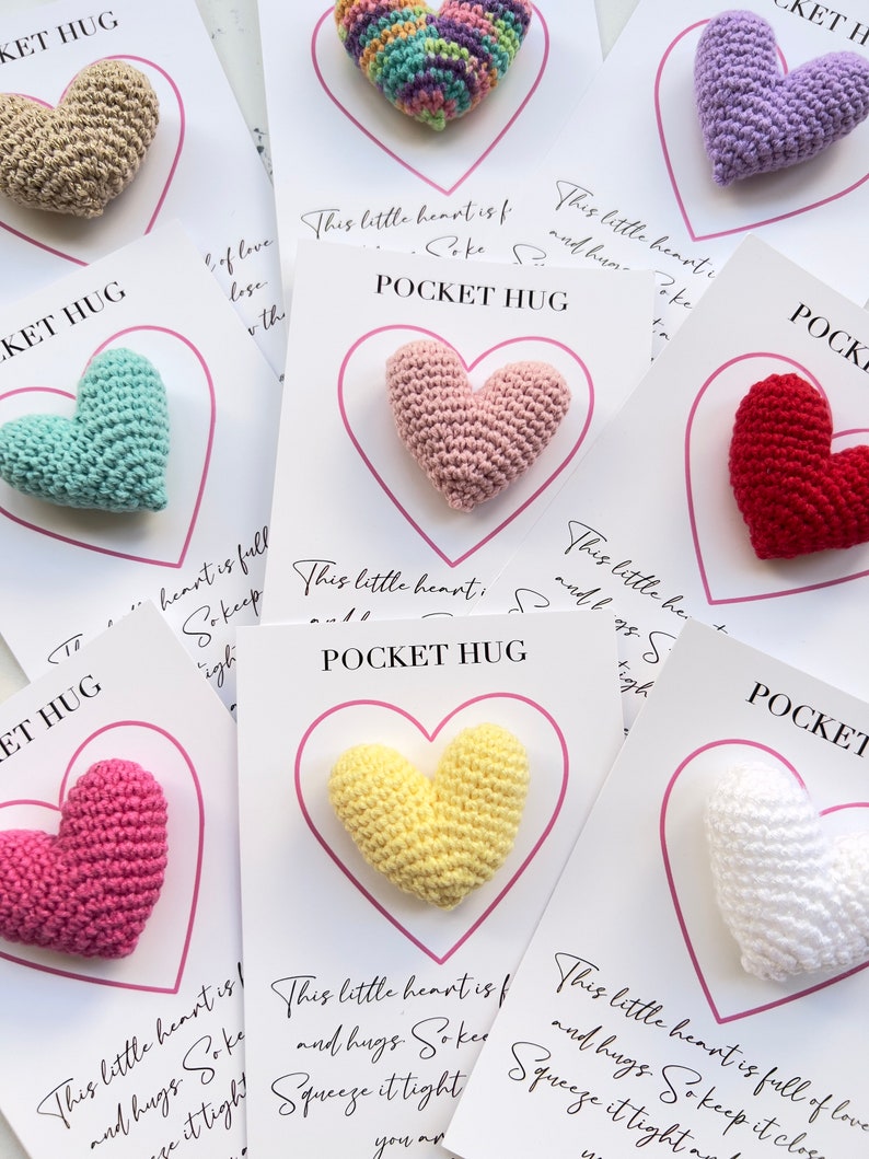 May include: A set of eight crocheted heart-shaped pocket hugs, each with a different color and a card that reads "This little heart is full of love and hugs. So keep it close. Squeeze it tight. You are loved."
