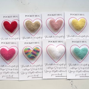 May include: Ten small crocheted hearts in various colors, each attached to a white card with the text "Pocket Hug" and a message about love and hugs.
