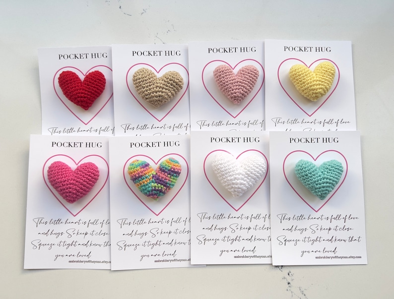 May include: Ten small crocheted hearts in various colors, each attached to a white card with the text "Pocket Hug" and a message about love and hugs.