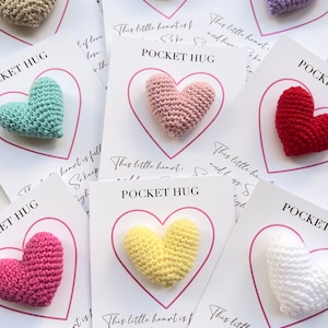 May include: A set of eight crocheted heart-shaped pocket hugs, each with a different color and a card that reads "This little heart is full of love and hugs. So keep it close. Squeeze it tight. You are loved."