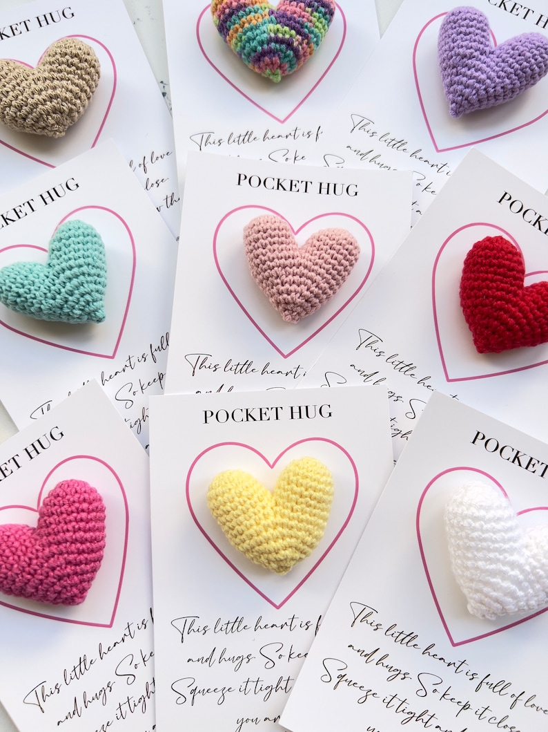 May include: A set of eight crocheted heart-shaped pocket hugs, each with a different color and a card that reads "This little heart is full of love and hugs. So keep it close. Squeeze it tight. You are loved."
