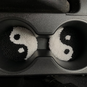 Peut inclure: Deux porte-gobelets de voiture yin yang noir et blanc. Les porte-gobelets sont faits d'un mat&eacute;riau doux et duveteux.