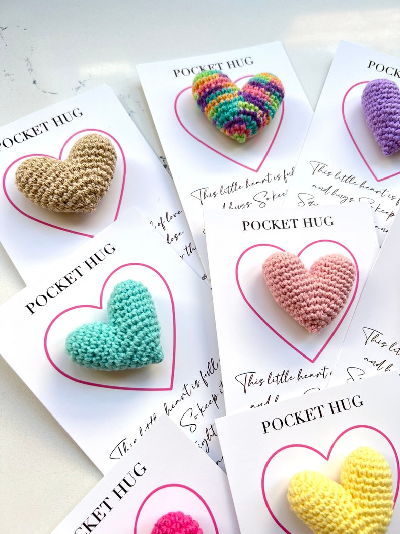 May include: A set of six crocheted heart-shaped pocket hug cards. Each card features a different color heart and the text "Pocket Hug" and a message about keeping the heart close.