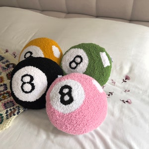 May include: Four plush pillows shaped like eight balls in yellow, green, black, and pink.