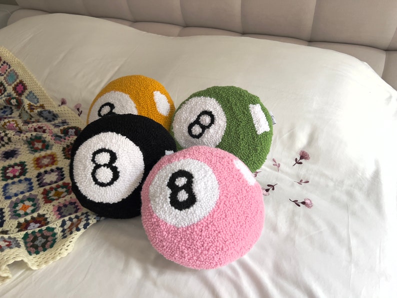 May include: Four plush pillows shaped like eight balls in yellow, green, black, and pink.