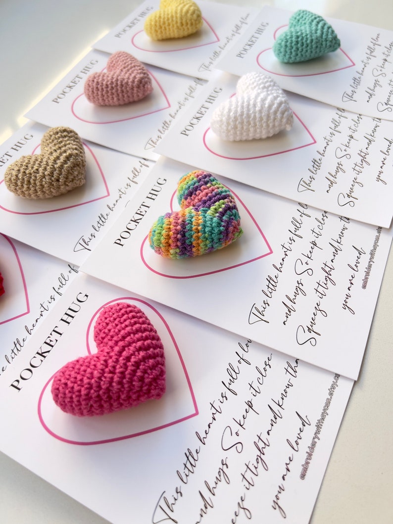 May include: Ten small crocheted hearts in various colors, each attached to a card with the text "This little heart is full of love and hugs. So keep it close. Squeeze it tight and know that you are loved."  The cards are labeled "Pocket Hug".