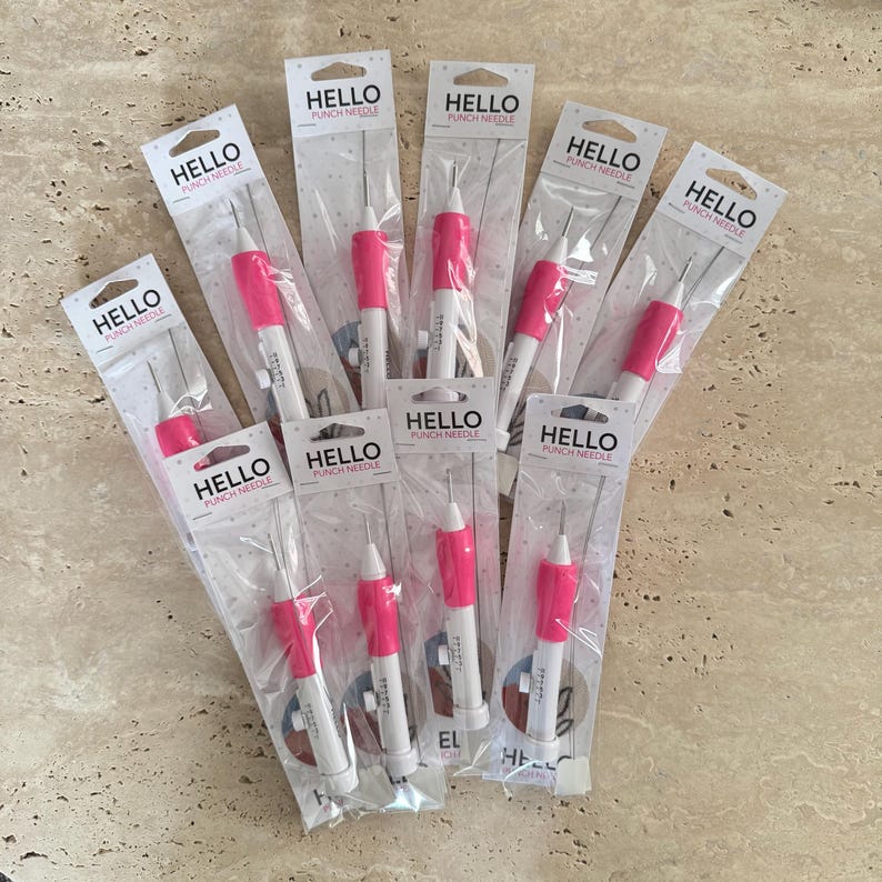 May include: Ten pink and white punch needles individually packaged in clear plastic bags. Each package has the text "HELLO PUNCH NEEDLE" printed on it.