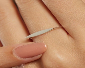 May include: A silver ring with a thin, flat, pointed oval-shaped band.