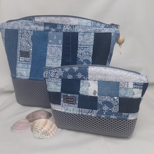 Könnte beinhalten: Zwei blaue Kosmetiktaschen mit Patchwork und Reißverschluss. Die Taschen bestehen aus Jeans- und Paisley-Stoffen in verschiedenen Blautönen. Der Boden jeder Tasche ist aus grauem Mesh. Eine kleine Holzperle hängt am Reißverschluss der größeren Tasche.