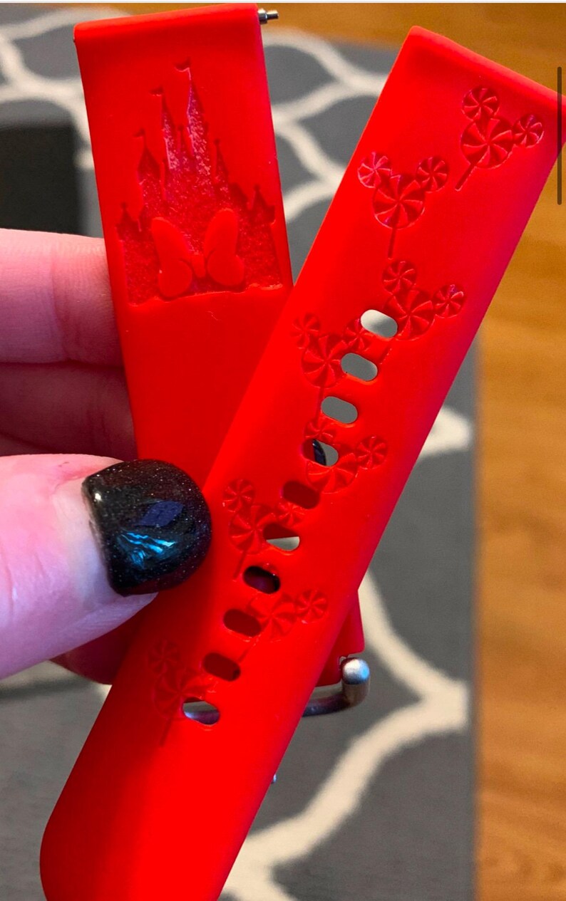 May include: Two red silicone watch bands with a Disney theme. One band features a silhouette of Cinderella's castle with the text "100" and the other band has a repeating pattern of Mickey Mouse heads.