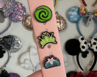 Puede incluir: Una banda rosa para Apple Watch con tres pines de esmalte verde, azul y blanco. Los pines presentan diseños inspirados en las películas animadas de Disney.