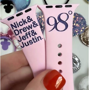 May include: Two pink Apple Watch bands with different designs. One band has the text "Nick & Drew & Jeff & Justin." The other band has the text "98°".