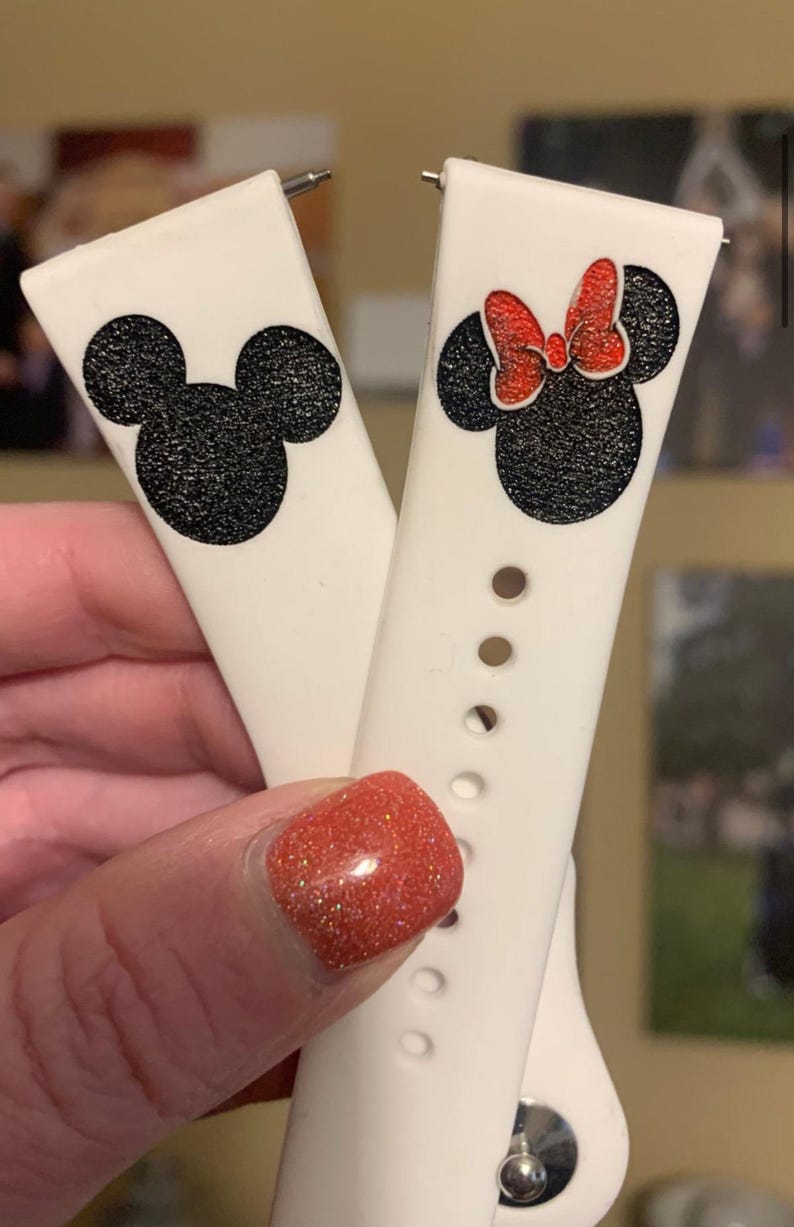 May include: Two white silicone watch bands with black and red glitter Mickey Mouse and Minnie Mouse designs. The bands have silver metal clasps.