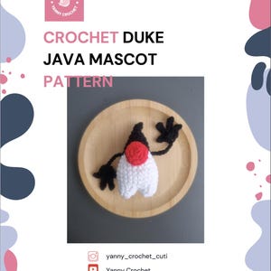 May include: A crocheted Duke Java Mascot pattern. The mascot is white with a red circular face and a black top. It has black arms and is displayed on a wooden plate. The image also includes the text "CROCHET DUKE JAVA MASCOT PATTERN".
