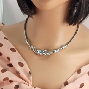 Op de afbeelding: Een zilveren chokerketting met een decoratief, gedraaid en getextureerd ontwerp.