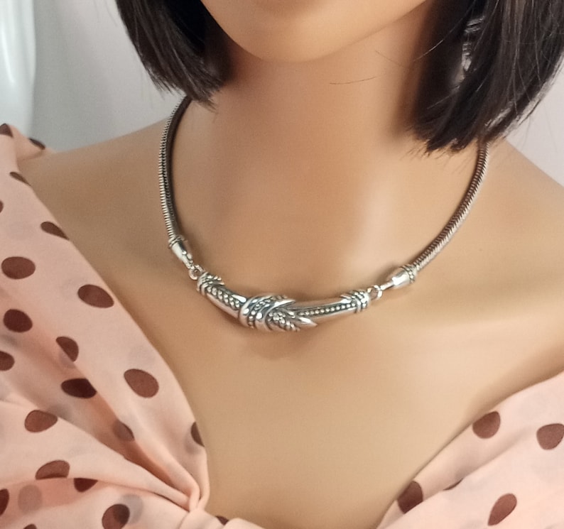Op de afbeelding: Een zilveren chokerketting met een decoratief, gedraaid en getextureerd ontwerp.
