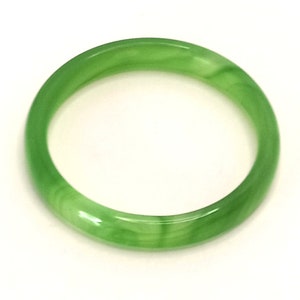 May include: A green jade bangle bracelet. The bangle is smooth and polished, with a light green color.