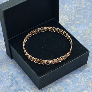 May include: A gold-toned braided bangle bracelet in a black velvet jewellery box.