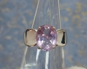 May include: A silver ring featuring a large oval amethyst gemstone. The ring has two silver bands on either side of the stone.