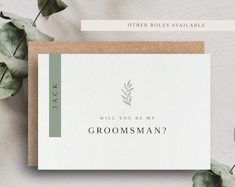 May include: A white card with green accents and a simple line drawing of a branch. The card reads "Will you be my groomsman?" with the name "Jack" printed on the left side and "The Twenty Six Co" at the bottom.