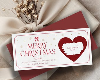 May include: A rectangular Christmas scratch-off card with a white background, red text reading MERRY CHRISTMAS, a red bow, gold snowflakes, and a large red heart containing a white scratch-off area with the text Your suprise here!.