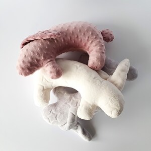 Puede incluir: Tres juguetes de peluche con forma de conejos. Los conejos son rosa, blanco y gris. El conejo rosa est&aacute; encima del conejo blanco, y el conejo gris est&aacute; en la parte inferior.