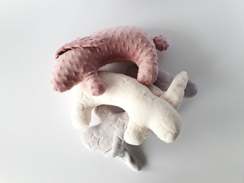 Puede incluir: Tres juguetes de peluche con forma de conejos. Los conejos son rosa, blanco y gris. El conejo rosa est&aacute; encima del conejo blanco, y el conejo gris est&aacute; en la parte inferior.