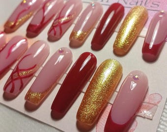Lange ballerina-nagels met herbruikbare Franse nagels in bordeauxrood, goud en rode glitter.