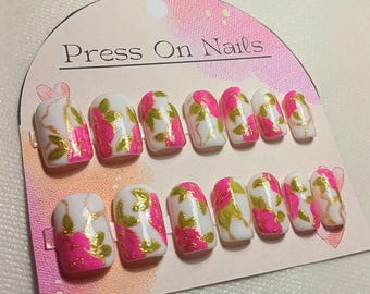 Korte, vierkante, witte plaknagels met fuchsia rozen, groene bladeren en een gouden rand, handgemaakt en herbruikbaar.