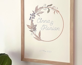 May include: Framed print with a botanical wreath design. The print features the names "Anna & Florian" and the date "23. Mai 2023". The text "We said Yes" is at the top. The frame is made of light-colored wood.
