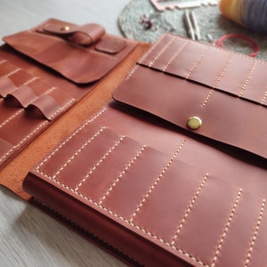 May include: A brown leather organizer with multiple pockets and slots, perfect for storing and carrying tools or supplies. The organizer has a flap closure and a gold button.