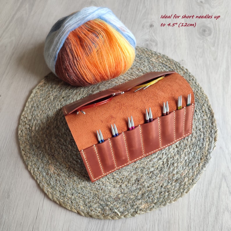 May include: A brown leather knitting needle roll with 10 slots for needles up to 4.5 inches (12 cm) long. The roll is open and shows the slots with needles inside.  Ideal for short needles up to 4.5" (12cm).