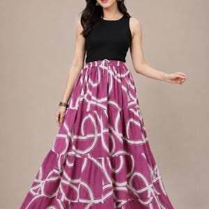 Op de afbeelding: Een zwarte mouwloze tanktop met ribbelstructuur gecombineerd met een lange, gelaagde magenta rok met een wit cirkelvormig geometrisch patroon. De rok heeft een geplooide elastische tailleband met een trekkoord en een wijde pasvorm.