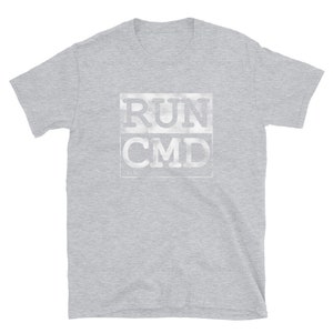 K&ouml;nnte beinhalten: Ein hellgraues T-Shirt mit kurzen &Auml;rmeln und einem wei&szlig;en Aufdruck mit der Aufschrift "RUN CMD" in einer verwitterten Schriftart.