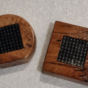 May include: Two wooden coasters with a black square inlay featuring a word search puzzle. The words in the puzzle include "twenty", "quarter", "five", "half", "pastor", "eight", "three", "six", "eleven", "twelve", "four", and "nine".