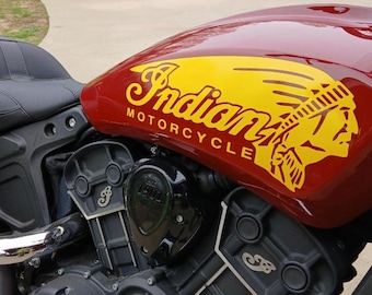 May include: A red motorcycle with a yellow Indian Motorcycle logo and a Native American headdress graphic. The motorcycle has a black seat and black engine.