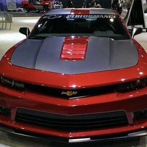 May include: A red Chevrolet Camaro with a black and red hood stripe and a "PERFORMANCE" windshield banner.