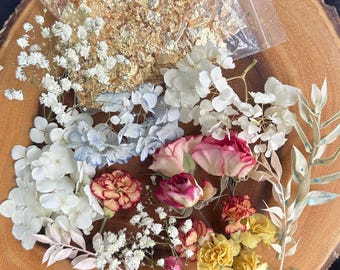 Könnte beinhalten: Eine Sammlung getrockneter Blumen, darunter weißes Schleierkraut, weiße und hellblaue Hortensienblüten, rosa und gelbe Nelken sowie grünes Blattwerk, ergänzt durch einen kleinen, durchsichtigen Plastikbeutel mit Blattgoldflocken.