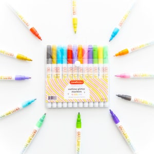 May include: A set of 12 outline glitter markers in a clear plastic case. The markers are arranged in a rainbow pattern and have the words "outline glitter markers" and "12 colors" printed on the case.