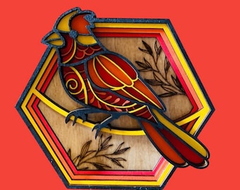 May include: A hexagonal wooden wall art piece featuring a red cardinal bird with intricate details. The bird is surrounded by a multi-layered frame with shades of yellow, orange, and red.