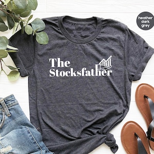 May include: A heather dark grey t-shirt with the text "The Stocksfather" and a white graphic of a rising stock chart.