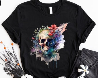 May include: Black t-shirt with a watercolor skull design surrounded by colorful flowers. The skull is white with black eye sockets and a blue nose.