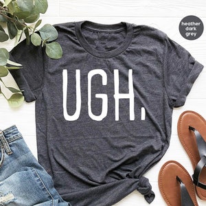 May include: A heather dark grey t-shirt with the word "UGH." printed in white.