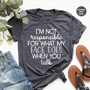 May include: A heather dark grey t-shirt with the text "I'M NOT responsible FOR WHAT MY FACE DOES WHEN YOU talk" printed in white.