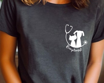 May include: Dark gray t-shirt with a white graphic of a stethoscope, cat, and dog, with the word "Receptionist" below. The shirt is a crew neck style.